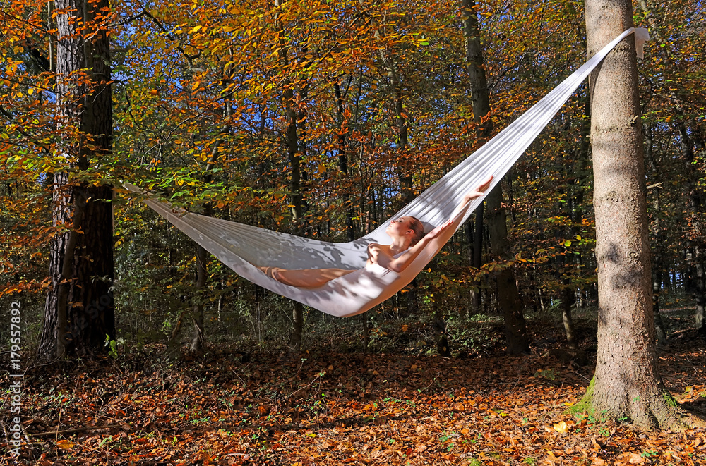 A beautiful young woman lies naked in a self made hammock tied between two  trees. Around her the forest in all its Autumn colors. Stock Photo | Adobe  Stock
