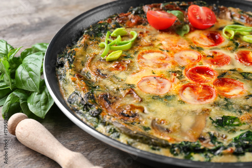 Frying pan with delicious spinach frittata on table, closeup
