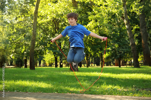 Cute little boy jumping rope in park