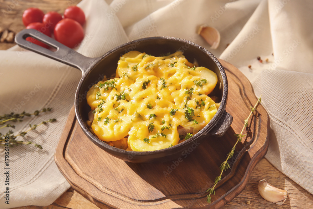 Board with delicious potato casserole in pan on table Board with delicious potato casserole in pan on table