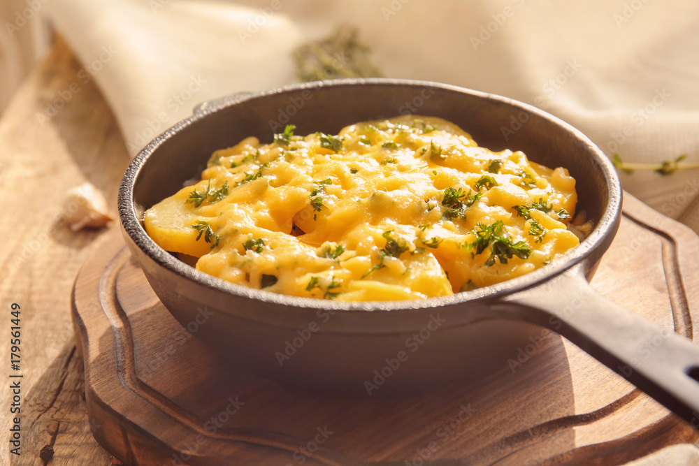 Board with delicious potato casserole in pan on table Board with delicious potato casserole in pan on table