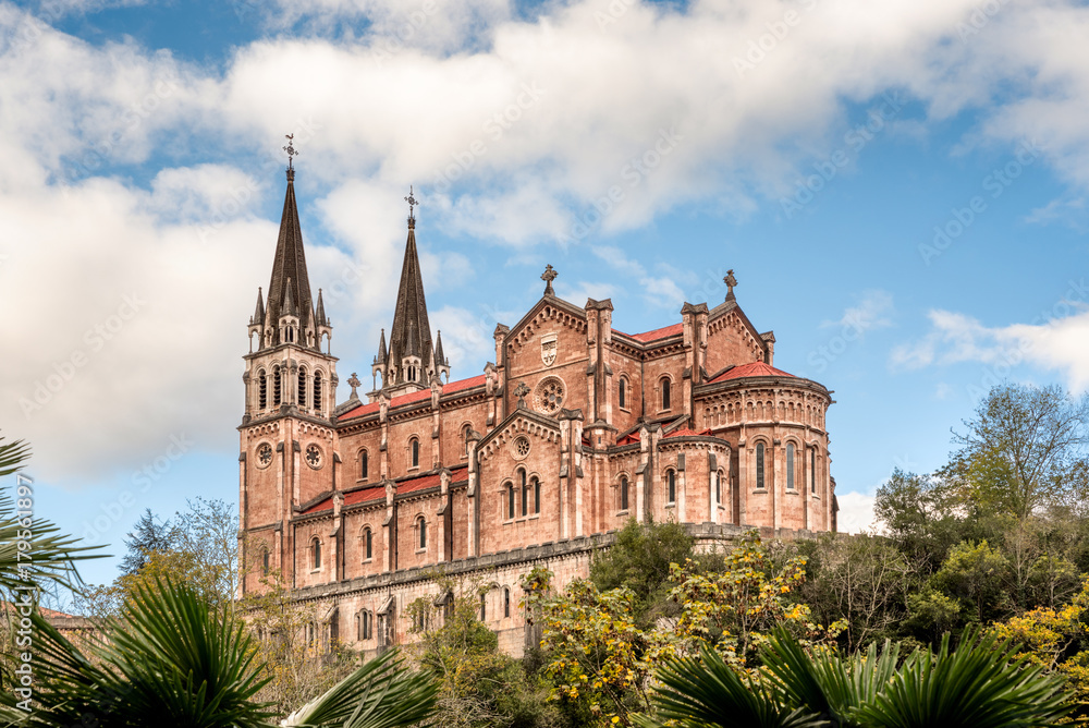 Obraz premium Basilica of Santa Maria la Real de Covadonga, Asturias, Spain, Europe. Beautiful church touristic travel destination landmark with a vibrant colorful sky and green natural foliage.