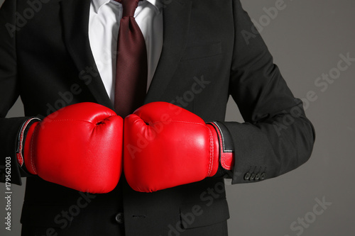 Businessman in boxing gloves on grey background © Africa Studio