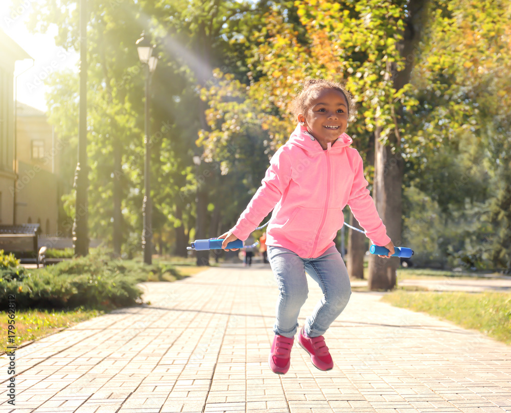 Cute African American girl skipping rope, outdoors Cute African American girl skipping rope, outdoors
