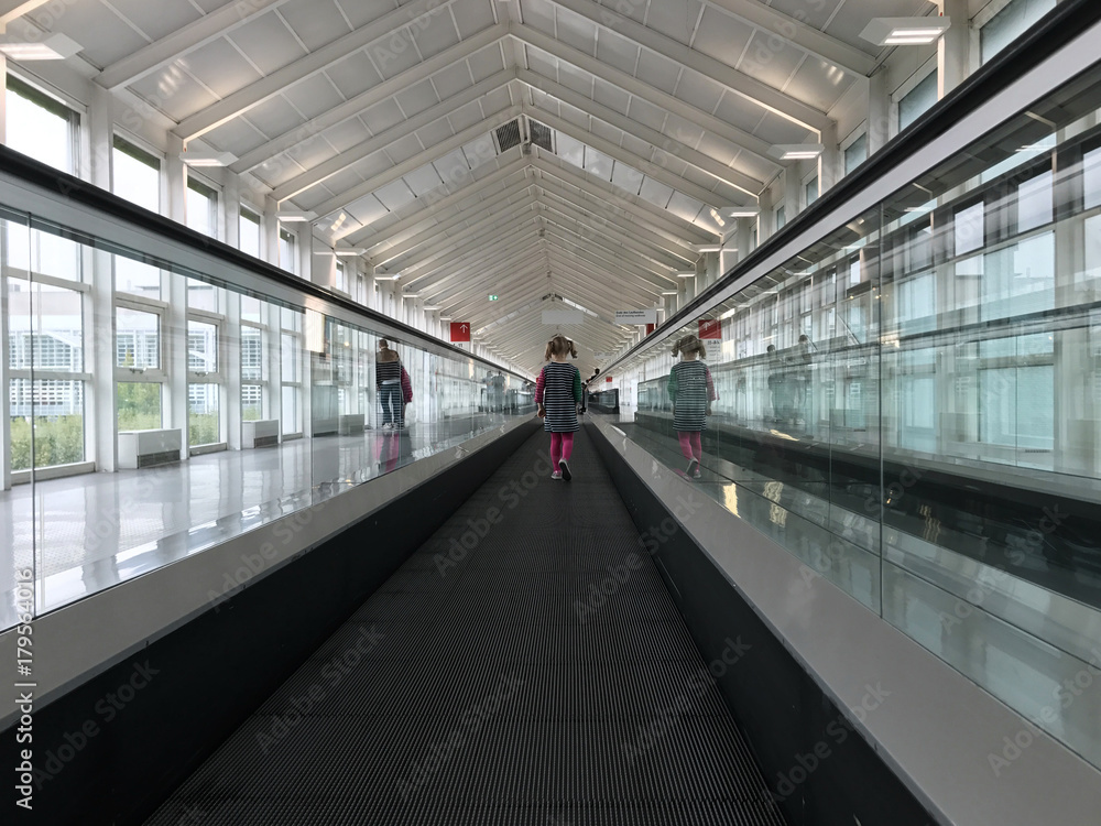Lonely cute child travelling on travelator at airport terminal