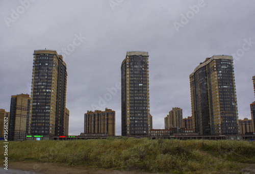  New high-rise houses and a field of grass, a new district of the city built in the field, the view of the new building, the outskirts of the big city in the fall.