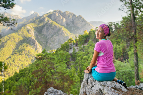 Young tourist woman is sitting on the top of the mounting and looking at a beautiful landscape, Turkey Goynuk canyon