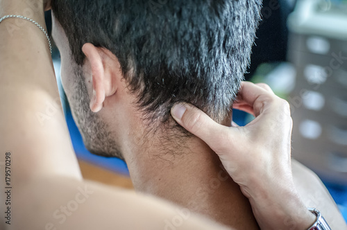 fisioterapista massaggia giovane paziente per curare un dolore cervicale photo