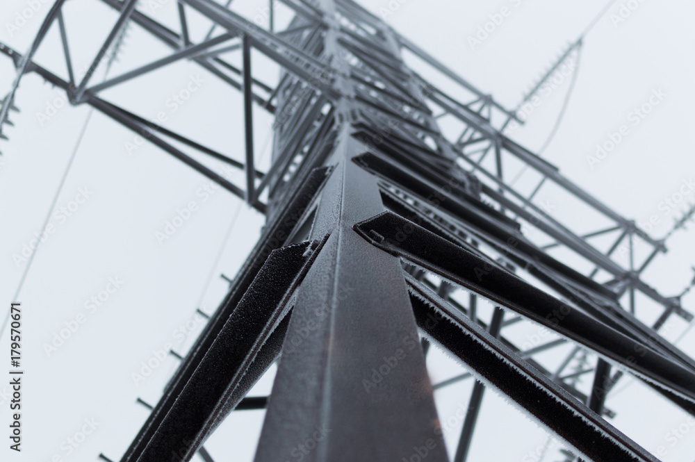 Closeup atmospheric photo of the perspective of the high voltage transmission tower covered with hoarfrost standing on the gray sky background after blizzard Closeup atmospheric photo of the perspective of the high voltage transmission tower covered with hoarfrost standing on the gray sky background after blizzard