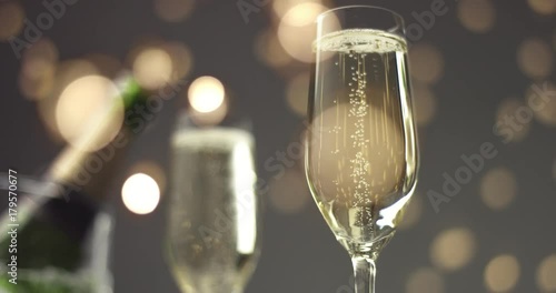 Bubbles going up in thin flute champagne glasses on a holiday table with a bottle of champagne in ice basket