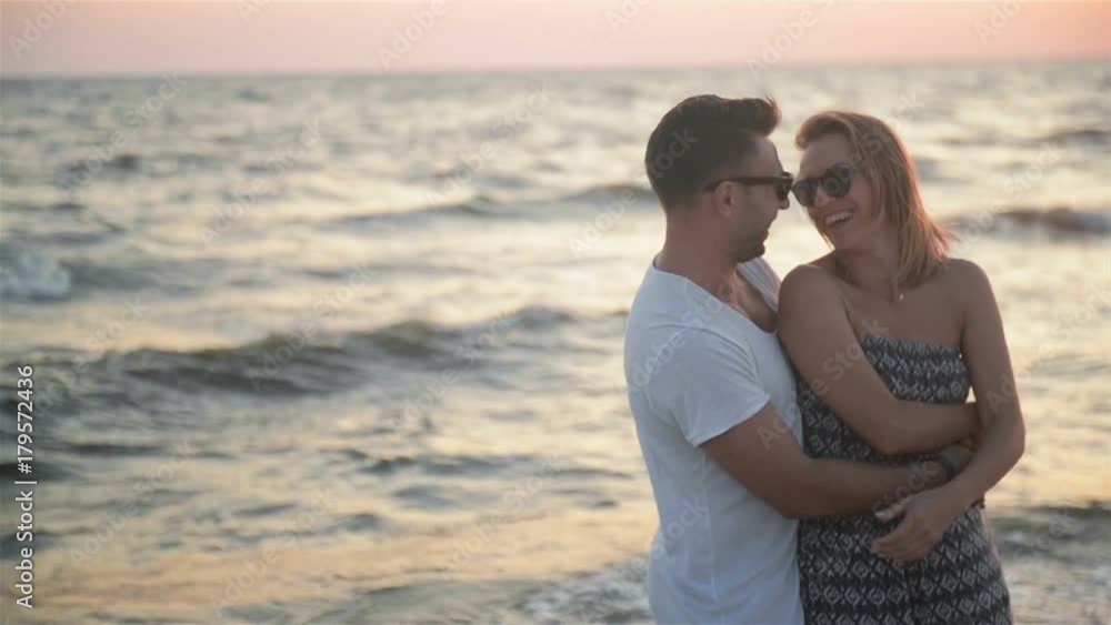 Hansome Boyfriend Hugging His Blonde Girlfriend Standing Near the Sea During Sunset. Hansome Boyfriend Hugging His Blonde Girlfriend Standing Near the Sea During Sunset.