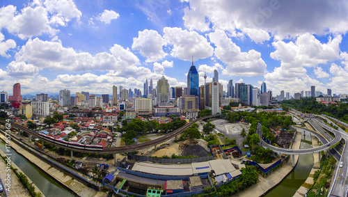 Panorama view of Kuala Lumpur city skyline with dramatic cloud formation and blue sky.