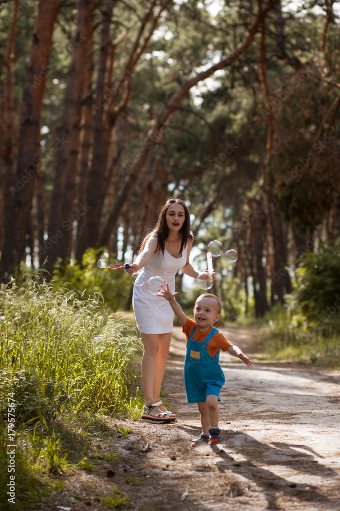 Happy mother baby bubble blowwing nature concept. Family moments. Sunny day in the forest. Happy mother baby bubble blowwing nature concept. Family moments. Sunny day in the forest.