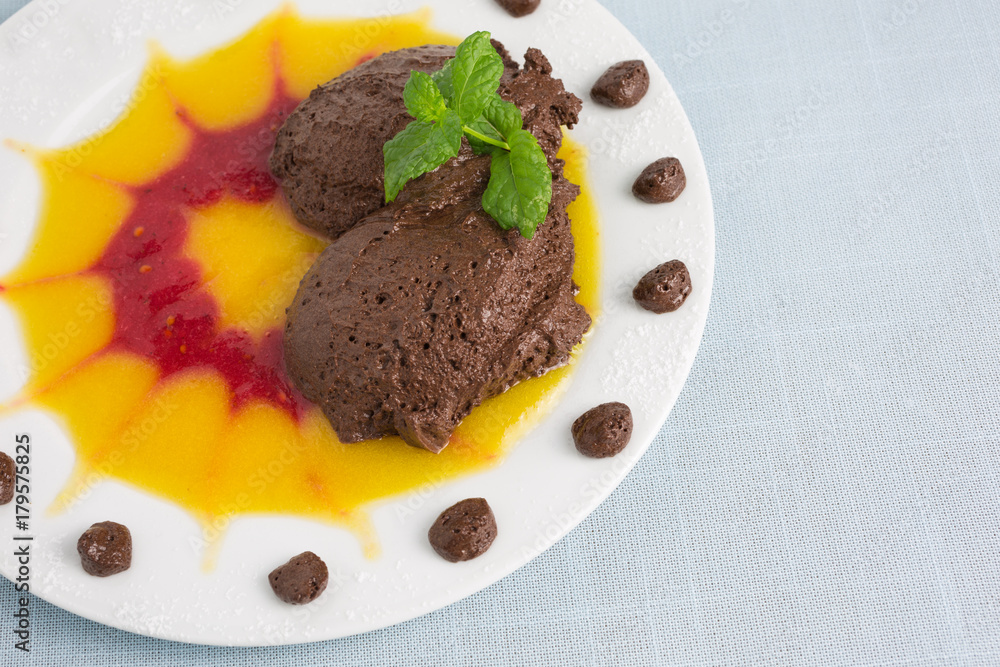 chocolate mousse on plate with pureed fruit in red and yellow chocolate mousse on plate with pureed fruit in red and yellow