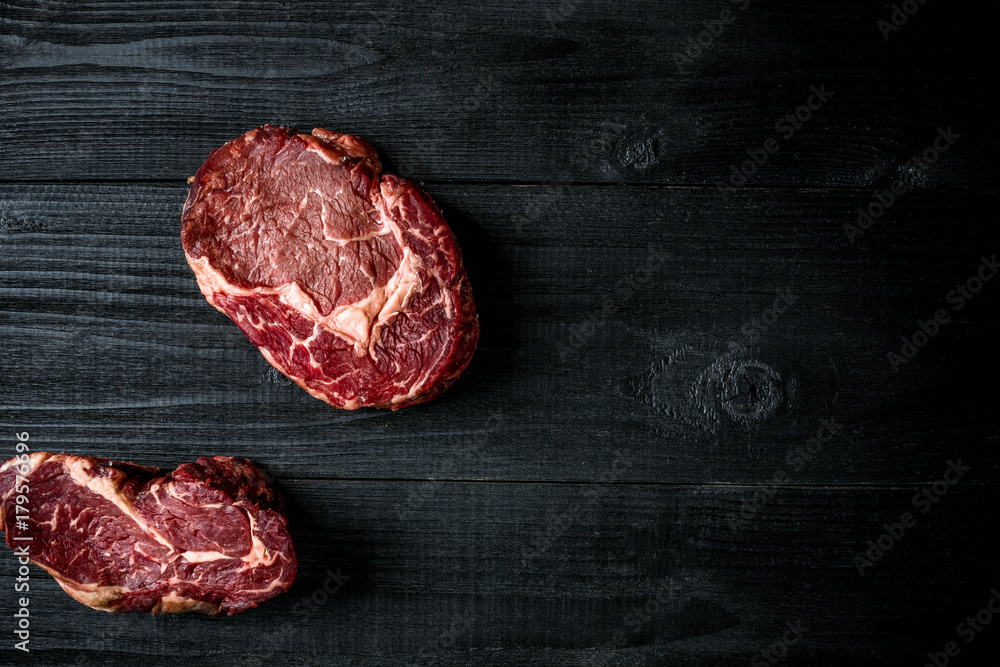 Fresh raw beef on black wooden background. Top view
