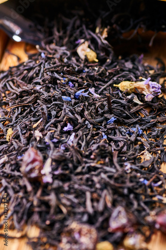 Dry tea leaves are scattered on the table. Indian tea with pieces of fruit and dried flowers. Tea time. Welding for the preparation of a fragrant hot winter drink. Chinese traditional tea closeup.