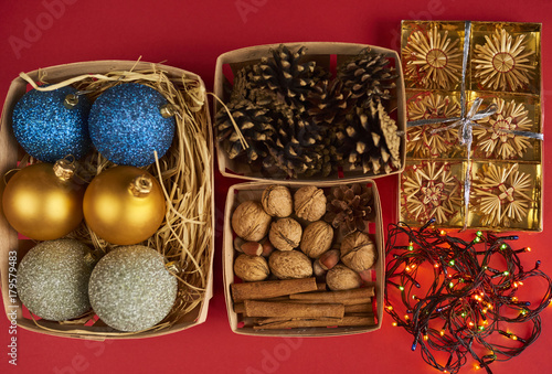 Christmas decorations, pine cones and nuts in boxes on red backround