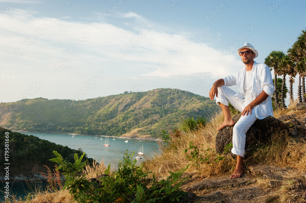 man sitting on a rock and looking at the sunset of Phuket