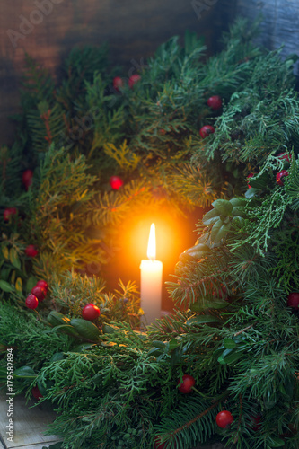 A Christmas wreath made of fir branches, juniper, tuja, boxwood and wild rose berries. Wreath with burning candles. photo