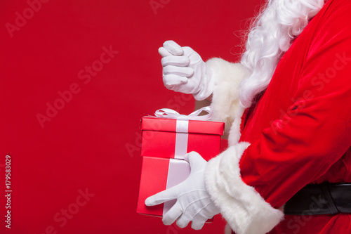 christmas Photo of Santa Claus gloved hand with red giftbox. no fig