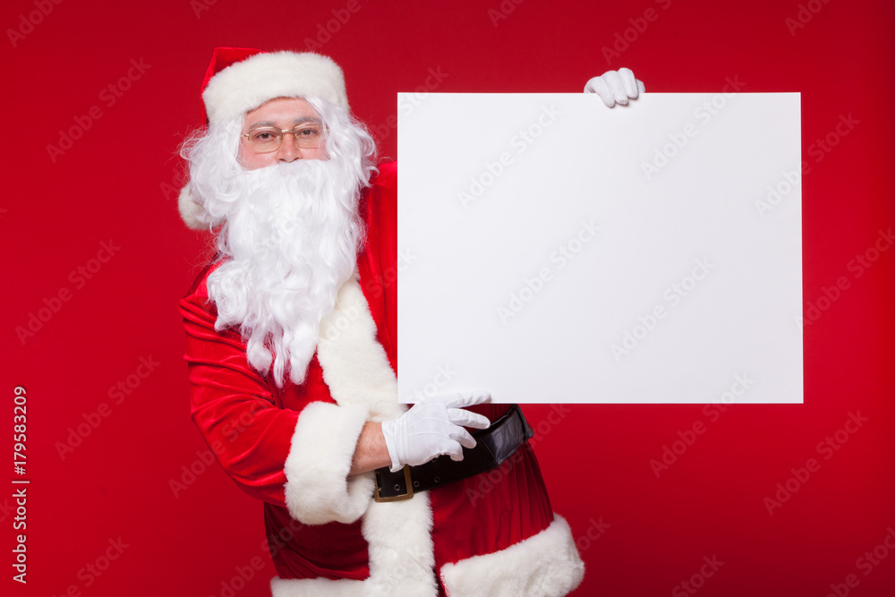Santa Claus pointing in blank advertisement banner isolated on red background with copy space Santa Claus pointing in blank advertisement banner isolated on red background with copy space