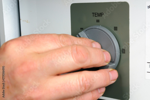 Man adjusts the thermostat on a domestic boiler