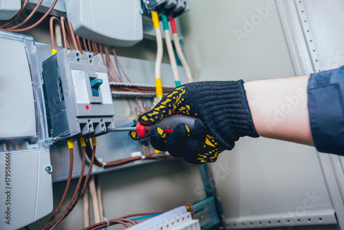 Electricians hands testing switches in electric box. Electrical panel with fuses and contactors