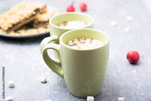 Two cup of hot coffee or chocolate and cake with marshmallow on grey background. Closeup.
