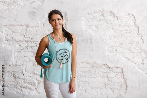 Wall Mural Portrait of attractive woman holding green yoga or fitness mat after working out at home or in club