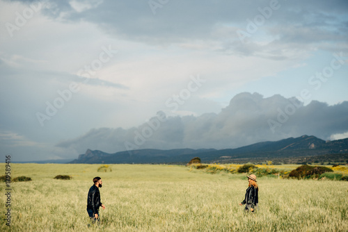 Happy loving couple walking around the field, mountains on the background © Vadim Pastuh