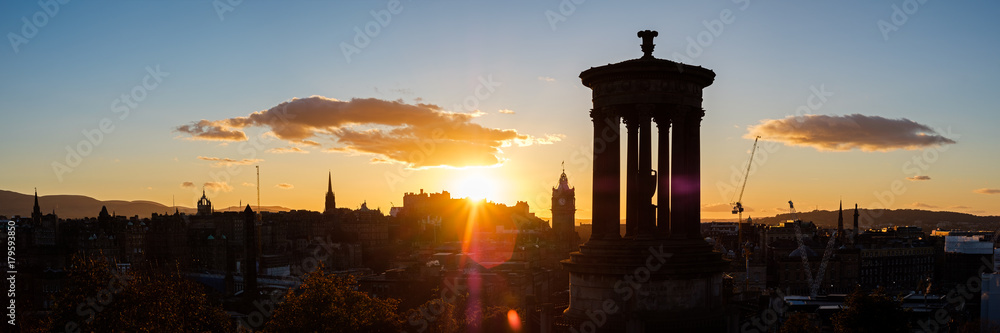 Summer view of Edinburgh's skyline at unset with the iconic Dugald Stewart Monument in the foreground and the Edinburgh Castle at the back. Scotland, UK