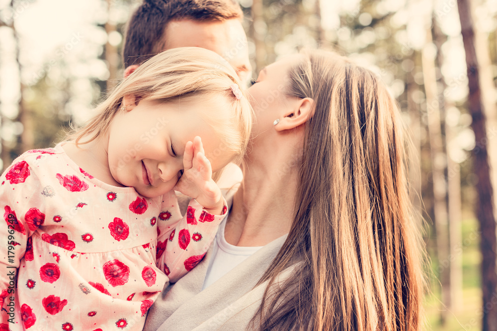 Young family of three having fun in a park enjoying their time together. Real people, real family, authenticity concept Young family of three having fun in a park enjoying their time together. Real people, real family, authenticity concept