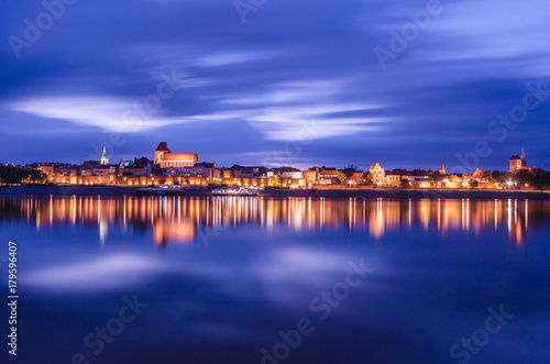 Torun at night. UNESCO-class medieval Old Town reflected in Vistula river, Poland. Europe.