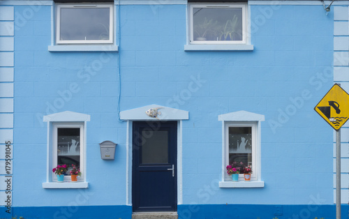 Maison bleue Irlandaise, avec chats sur rideaux et panneau de danger de circulation