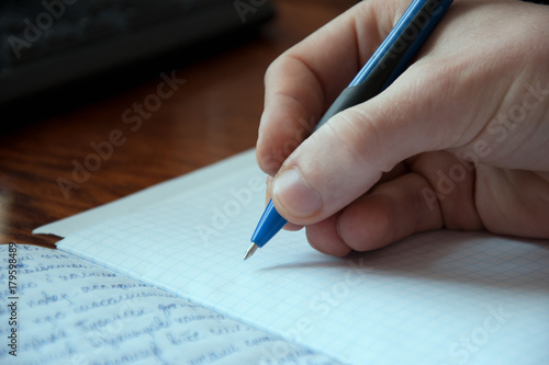 Hand that writes a pen in a copybook, process of a writing