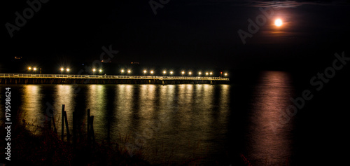 Widok na molo nocą w Gdyni Orłowo blisko klifu, księżyc odbija się w spokojnym morzu bałtyckim © blesz