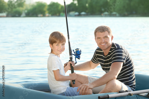 Father with son fishing from boat on river