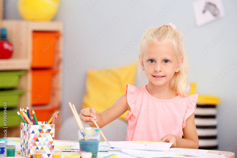 Cute girl painting at table indoor