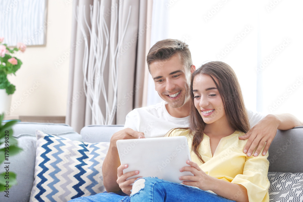 Young couple using tablet computer on sofa at home Young couple using tablet computer on sofa at home