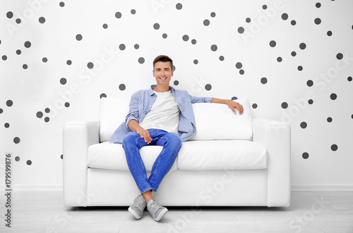 Young man on sofa near whit...