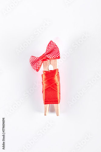 Clothespin in red apparel  white background. Wooden clothes peg in red dress and bow isolated on white background. Creativity and art.