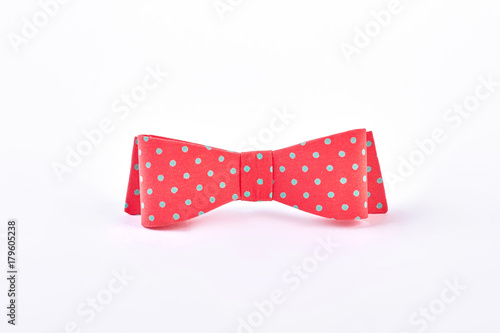 Red dotted bow tie on white background. Red bow for hair with blue spots. Trendy hair accessory.