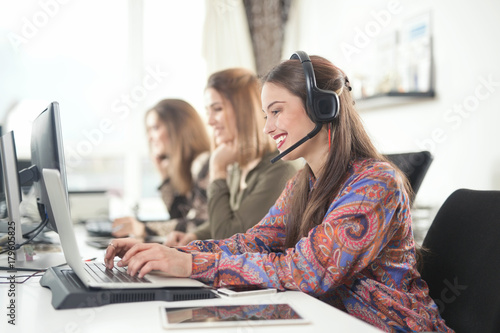 Portrait of cheerful young woman multi-tasking at her desk at work