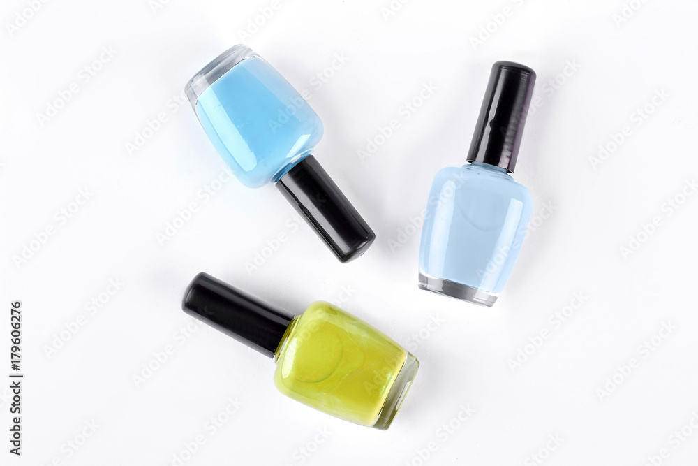 Obraz premium Colorful nail varnishes on white background. Nail polish set isolated on white background. Blue and yellow nail varnish.