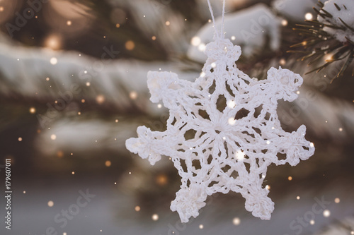Christmas white vintage crocheted snowflake on the branches of a snowy tree