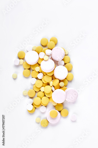 Pile of white and yellow pills. Heap of yellow and white vitamins or pills on white background, top view.