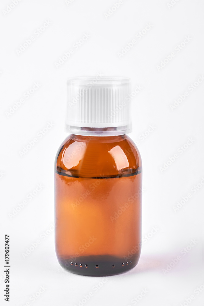Cough syrup in glass amber bottle. Antipyretic syrup in brown bottle with plastic measuring cup on white background. Cough syrup in glass amber bottle. Antipyretic syrup in brown bottle with plastic measuring cup on white background.