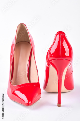 Red lacquered heels on white background. New elegant shoes on high heels for ladies. Female fashion footwear.
