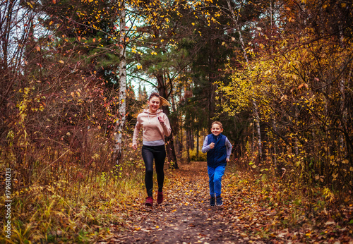 Little boy and his sister running in autumn forest