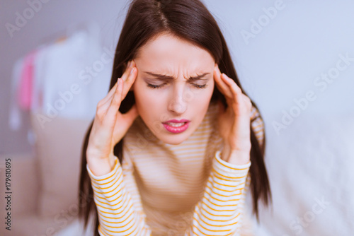Attractive concerned brunette woman sits and keeps hands her head
